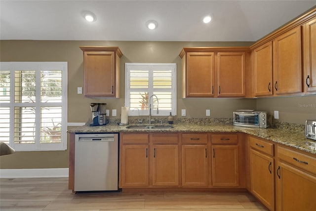 kitchen with a toaster, dishwasher, light stone counters, a sink, and recessed lighting