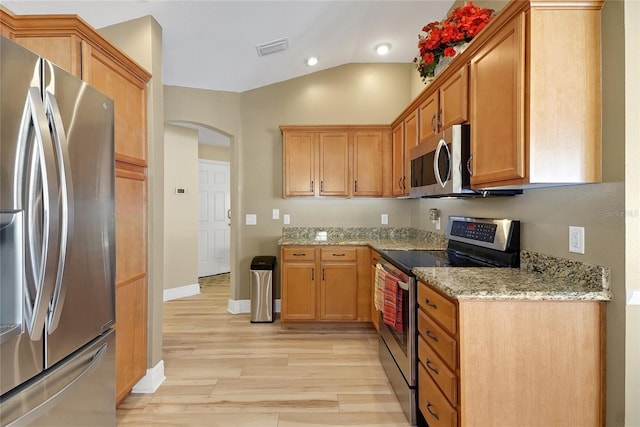 kitchen featuring arched walkways, light stone counters, visible vents, appliances with stainless steel finishes, and light wood finished floors