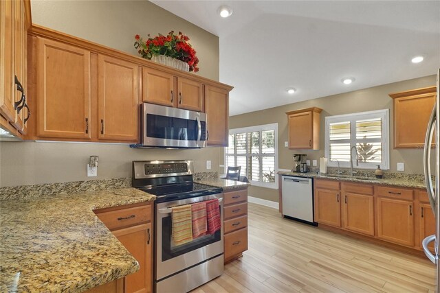 kitchen featuring light stone counters, light wood-style flooring, recessed lighting, stainless steel appliances, and a sink