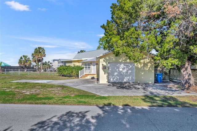 view of front of home with driveway, metal roof, an attached garage, fence, and a front yard