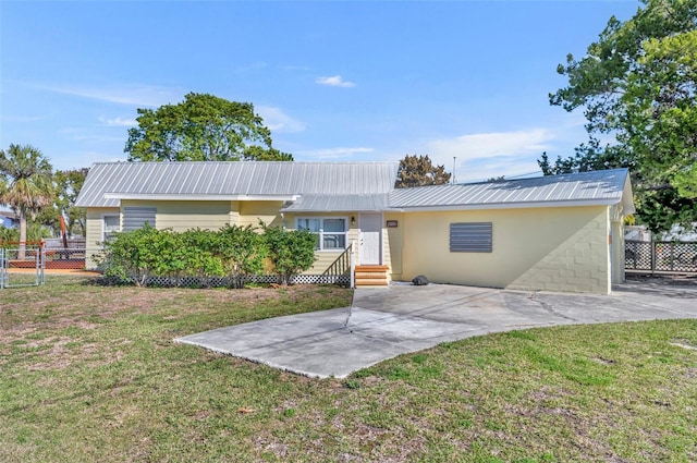 view of front of property with a front yard, entry steps, metal roof, and fence