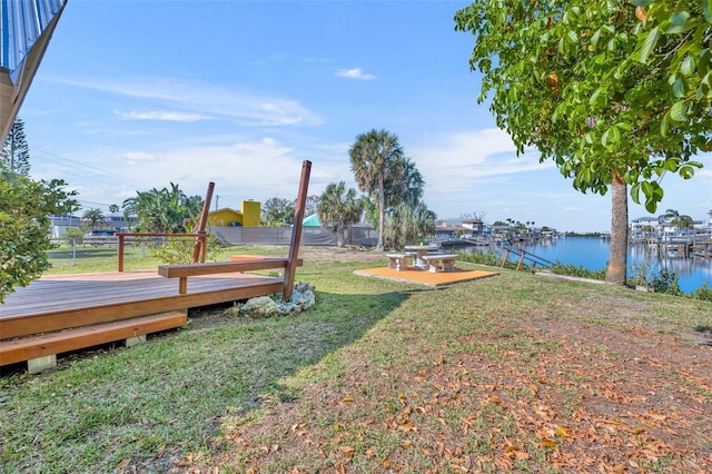 view of yard featuring a deck with water view and fence