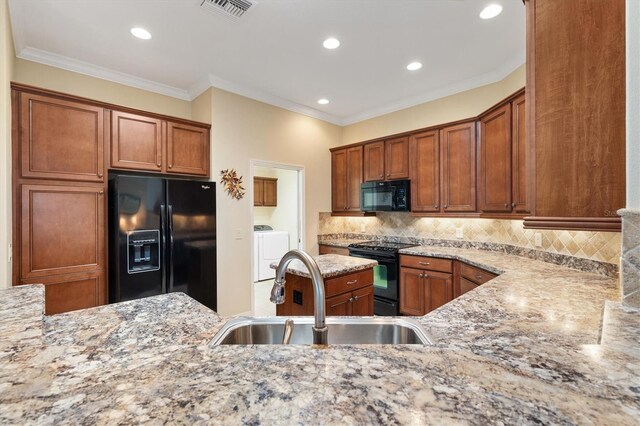 kitchen with visible vents, decorative backsplash, a sink, light stone countertops, and black appliances