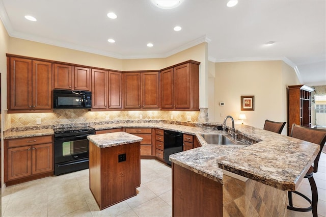 kitchen featuring light stone counters, a center island, a sink, a peninsula, and black appliances