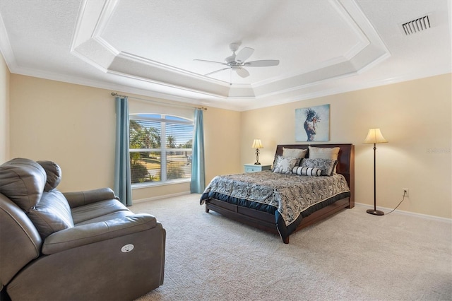 carpeted bedroom with baseboards, visible vents, a tray ceiling, and crown molding