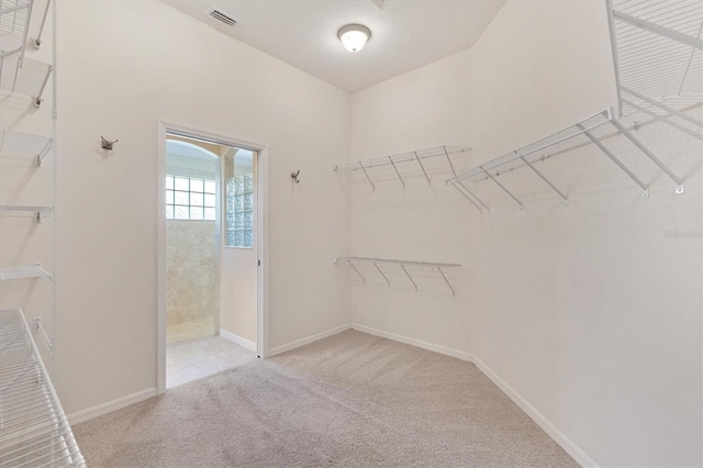 walk in closet featuring visible vents and light colored carpet