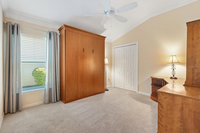 bedroom featuring baseboards, light colored carpet, lofted ceiling, ornamental molding, and a closet