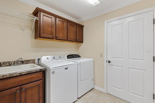 laundry room featuring cabinet space, crown molding, washer and dryer, a sink, and light tile patterned flooring