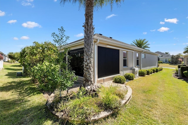 view of side of property with a sunroom, ac unit, and a yard