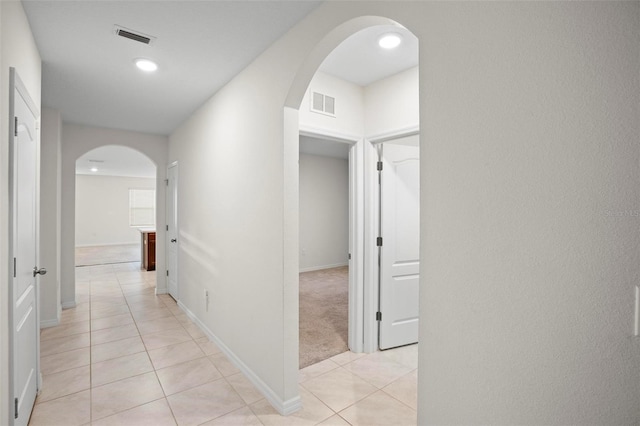 corridor with arched walkways, visible vents, and light tile patterned flooring