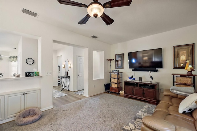 living area with light wood-style floors, visible vents, ceiling fan, and baseboards