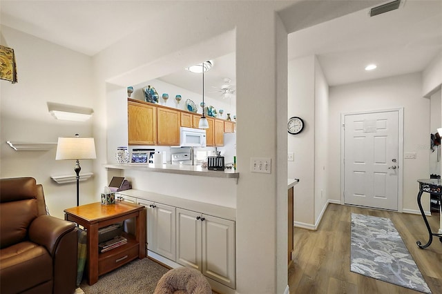 interior space featuring visible vents, white microwave, ceiling fan, wood finished floors, and baseboards