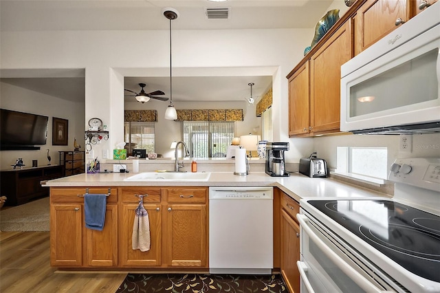 kitchen featuring white appliances, brown cabinets, a sink, and visible vents