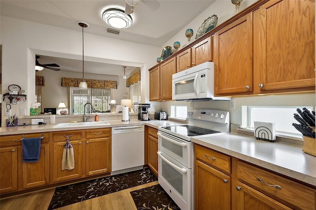 kitchen with white appliances, visible vents, ceiling fan, brown cabinets, and a sink