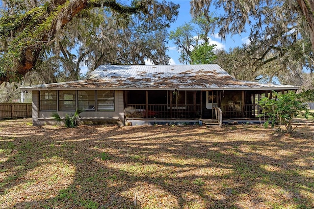 rear view of property with metal roof, fence, and a sunroom