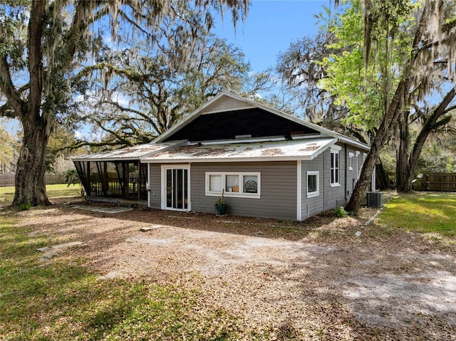 back of house featuring a sunroom, central AC unit, and metal roof