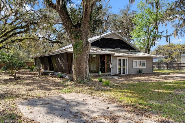 view of front facade featuring a sunroom, fence, and metal roof