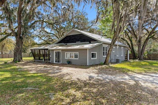 back of house featuring metal roof, central air condition unit, fence, a sunroom, and a yard