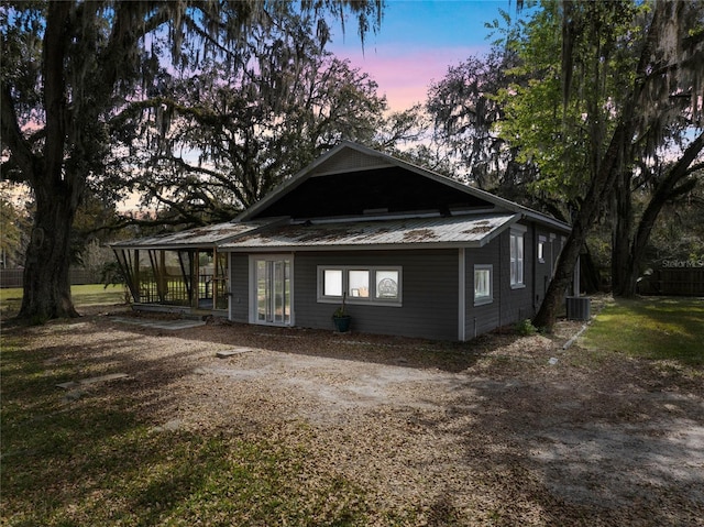 exterior space with metal roof, central AC unit, and a sunroom