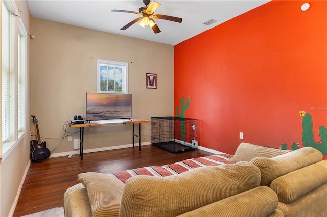 living area with a ceiling fan, visible vents, baseboards, and wood finished floors