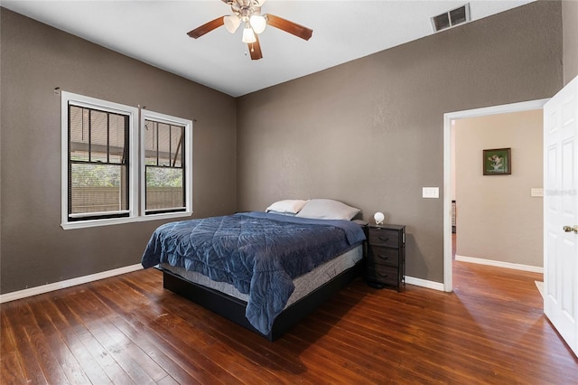 bedroom with a ceiling fan, visible vents, baseboards, and hardwood / wood-style flooring