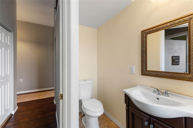 bathroom with toilet, baseboards, wood finished floors, and vanity