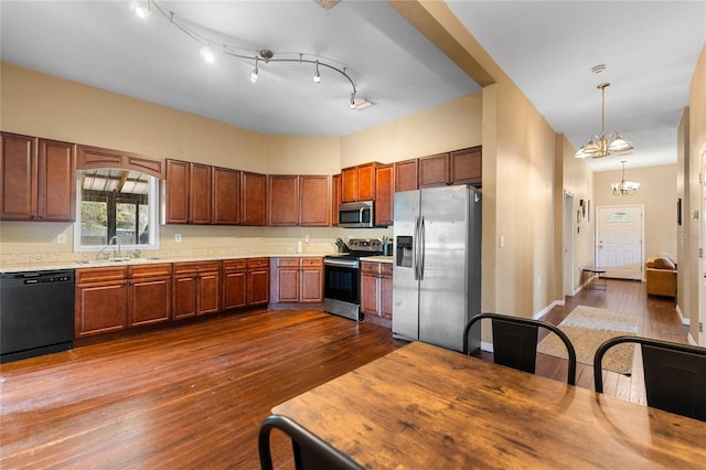 kitchen with dark wood finished floors, appliances with stainless steel finishes, an inviting chandelier, light countertops, and a sink