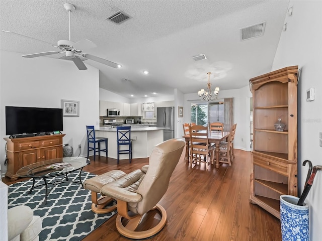 living area featuring lofted ceiling, visible vents, dark wood finished floors, and ceiling fan with notable chandelier