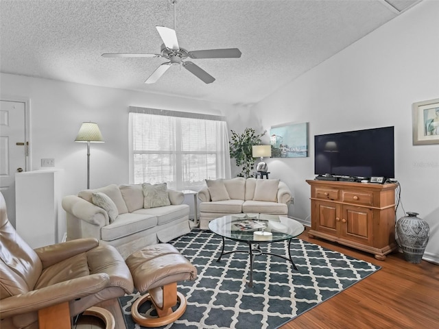 living room featuring ceiling fan, vaulted ceiling, a textured ceiling, and wood finished floors