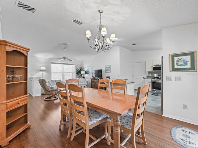 dining area with lofted ceiling, visible vents, a textured ceiling, and wood finished floors