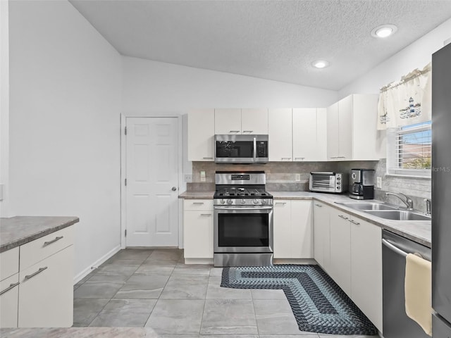 kitchen with lofted ceiling, a toaster, stainless steel appliances, a sink, and backsplash