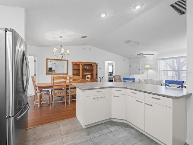 kitchen featuring light countertops, freestanding refrigerator, visible vents, and vaulted ceiling