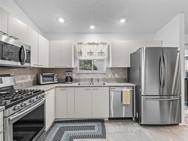 kitchen with a toaster, stainless steel appliances, a sink, light countertops, and tasteful backsplash