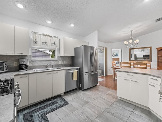 kitchen featuring appliances with stainless steel finishes, light countertops, a sink, and white cabinetry