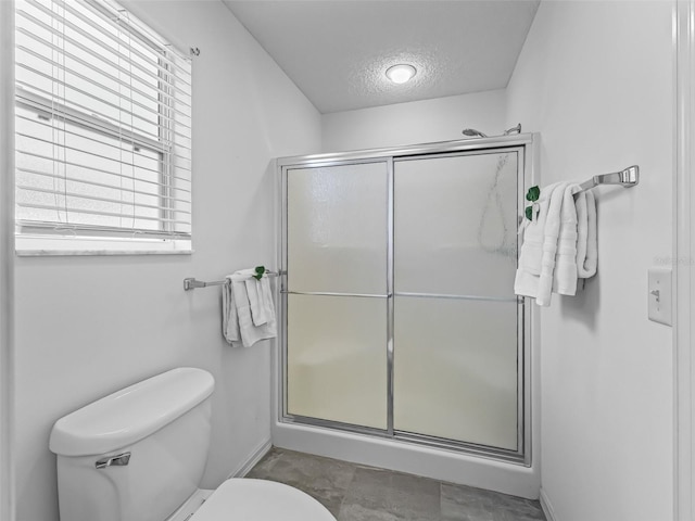 bathroom featuring a stall shower, baseboards, a textured ceiling, and toilet