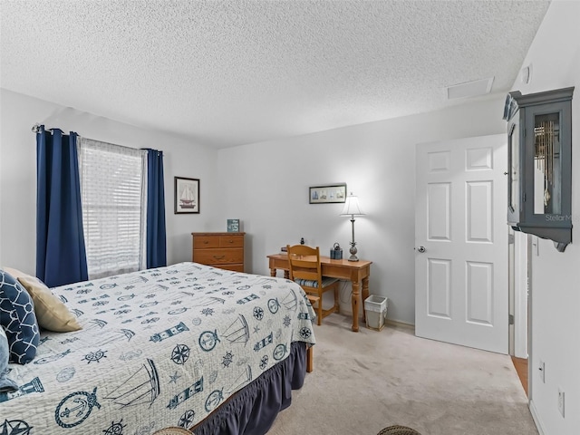 bedroom with attic access, light colored carpet, a textured ceiling, and baseboards