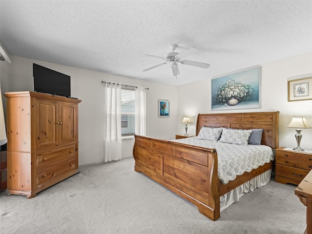 bedroom with a ceiling fan, light colored carpet, and a textured ceiling