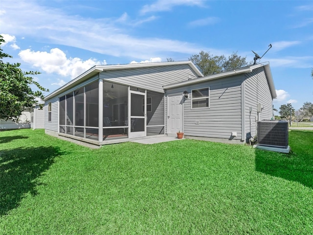 back of house featuring central air condition unit, a sunroom, and a yard