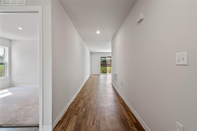 hall featuring a wealth of natural light, visible vents, and baseboards