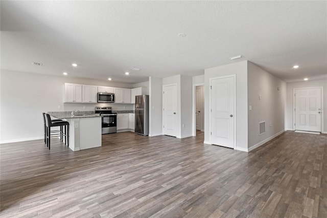 kitchen with stainless steel appliances, dark wood-style flooring, visible vents, white cabinets, and open floor plan