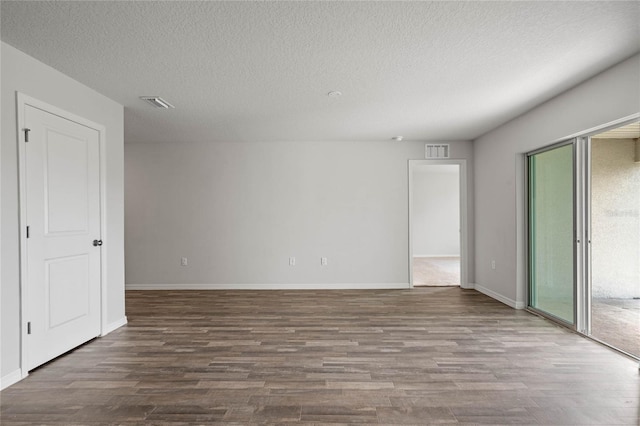 empty room featuring visible vents, baseboards, a wealth of natural light, and wood finished floors