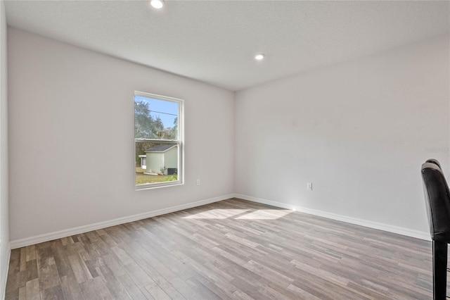 empty room featuring recessed lighting, wood finished floors, and baseboards