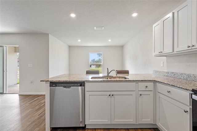 kitchen with dark wood-style flooring, stainless steel dishwasher, white cabinetry, a sink, and a peninsula