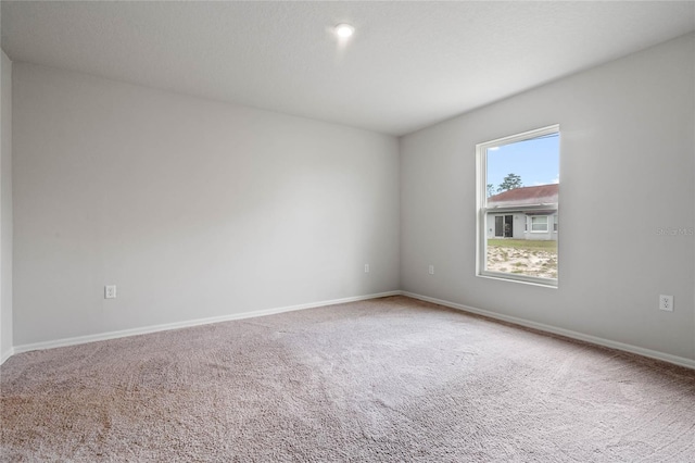 spare room featuring carpet floors and baseboards