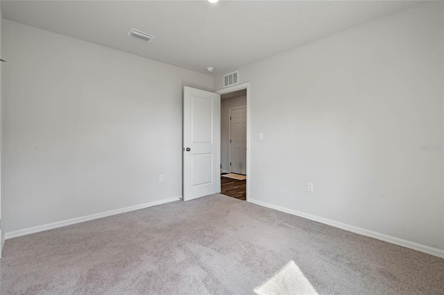 empty room with baseboards, visible vents, and carpet flooring