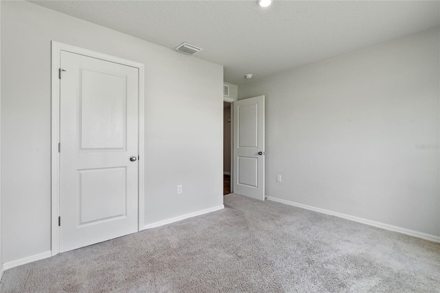 unfurnished bedroom with carpet, visible vents, and baseboards