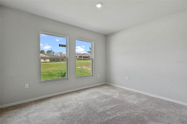 carpeted spare room with a textured ceiling and baseboards