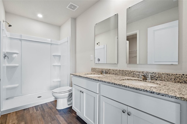 bathroom featuring wood finished floors, a stall shower, a sink, and visible vents