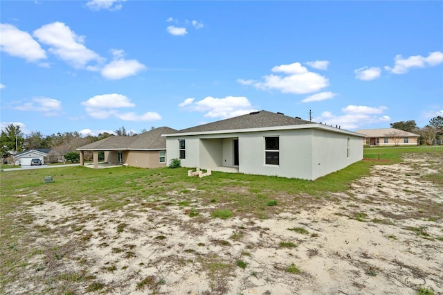 back of property featuring a yard and stucco siding