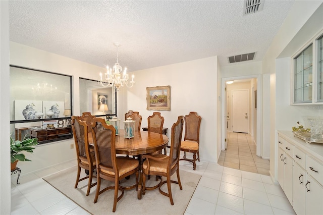 dining area featuring a textured ceiling, visible vents, and a notable chandelier